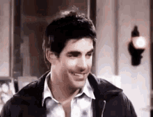 a man in a leather jacket is smiling and looking at the camera .