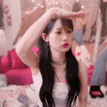 a woman with long black hair is sitting on a couch in a room with her hand on her head .