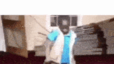 a man in a blue shirt and white vest is standing in a room .