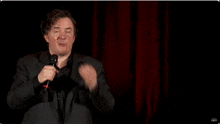 a man singing into a microphone with the word comedy on the bottom left