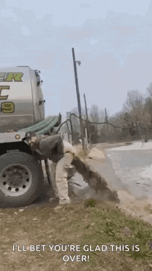 a man is standing next to a vacuum truck filled with water .
