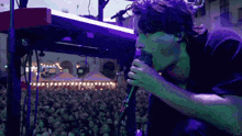 a man singing into a microphone with a crowd behind him