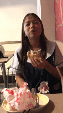 a woman sitting at a table with a plate of food and a hamburger