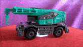 a kobelco toy truck is sitting on a red carpet