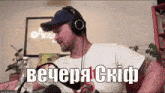 a man wearing headphones is sitting in front of a microphone with the words " вечеря скиф " written above him