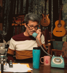 a man wearing glasses is talking on a phone next to a mug that says fire