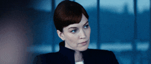 a woman in a black jacket looks at the camera with a serious look on her face