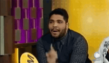 a man with a beard is sitting in front of a yellow sign that says ' riocoro ' on it