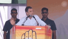 a man is standing at a podium giving a speech in front of microphones .