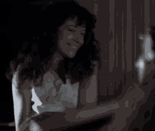 a woman in a white dress is sitting on a bed with her hair blowing in the wind .