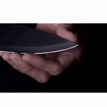 a person is holding a knife in their hand in a dark room .