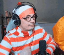 a man wearing headphones and a striped shirt is talking into a microphone .