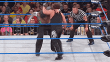 two wrestlers in a ring with a referee and a sign that says impact on it