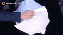 a person is holding a piece of paper with eltrecetv.com written on the bottom