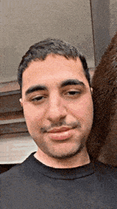 a man with a beard wearing a black shirt is smiling