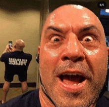 a bald man with a beard is taking a selfie in front of a mirror while wearing headphones .