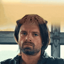 a man with a beard is wearing a hat with a cat 's head on it