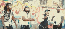a group of men wearing masks are dancing in front of a graffiti wall that says rk
