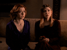 two women are sitting on a couch and one of them says " oh "