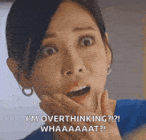 a woman is making a surprised face and holding her hand to her face .