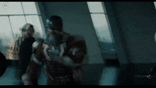 a man in a captain america costume is standing in a room with other people