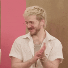 a man with blonde hair and a beard is applauding .