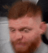 a blurry picture of a man with a beard making a face .