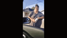 a very fat man is standing in front of a garage in a car .