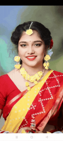 a woman wearing a red and yellow saree with a yellow necklace and earrings