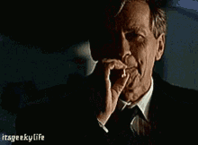 a man in a suit and tie is smoking a cigarette with the words itsgeekylife below him