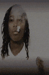 a man with dreadlocks is smoking a cigarette with smoke coming out of his nose