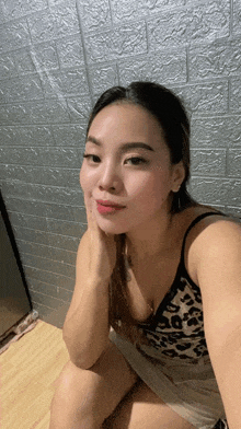 a woman in a leopard print tank top sits on a wooden floor