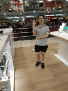 a woman wearing a grey shirt and black shorts is standing in a store