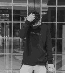 a black and white photo of a man wearing a sweatshirt that says ' kawaii ' on it