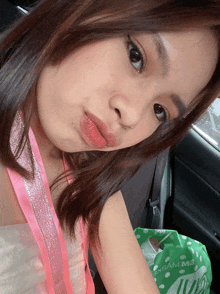 a woman sitting in a car next to a green bag that says ' yram m2 ' on it