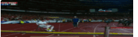 a blurred image of a track and field event with a man sitting on a bench