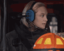 a woman wearing headphones and a helmet looks at the camera