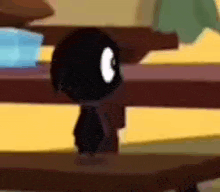a black cartoon character is standing on a wooden table .
