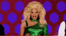 a drag queen with blonde hair is wearing a green dress and a choker .