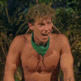 a shirtless man wearing a green bandana around his neck is smiling .