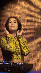 a woman in a yellow snake print top is wearing headphones and playing music .