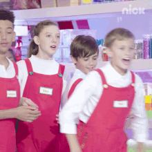 a group of kids wearing red aprons with a nick logo on the bottom