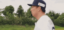 a man wearing a baseball cap and a white shirt is walking through a field .