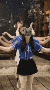 a girl wearing a cat mask is surrounded by other girls wearing baseball uniforms