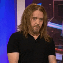a man with long hair and a beard is wearing a black t-shirt