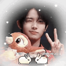 a young man is holding a stuffed animal and giving a peace sign with two rabbits .