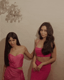 two women are standing next to each other in pink dresses