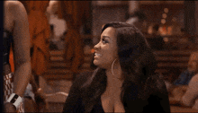 a woman is sitting at a table in a restaurant talking to a man .
