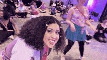 a woman with curly hair is smiling in a crowd