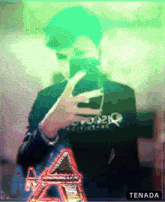 a man taking a picture of himself with a tenada logo in the background